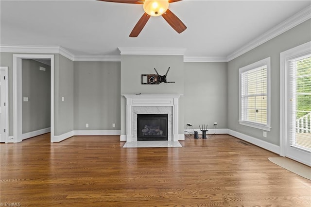 unfurnished living room featuring ornamental molding, wood finished floors, and a high end fireplace