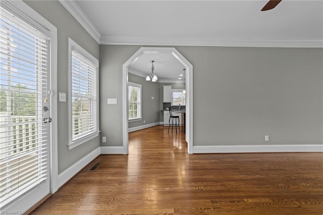 interior space featuring ceiling fan, visible vents, baseboards, dark wood-style floors, and crown molding