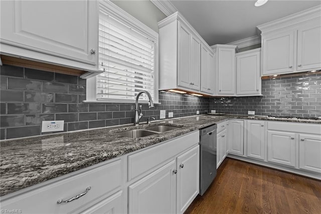 kitchen with appliances with stainless steel finishes, dark stone countertops, dark wood-style flooring, white cabinetry, and a sink