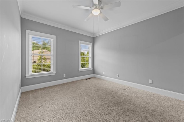 empty room featuring carpet flooring, a ceiling fan, visible vents, baseboards, and ornamental molding