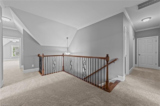 corridor with carpet floors, an upstairs landing, visible vents, and crown molding