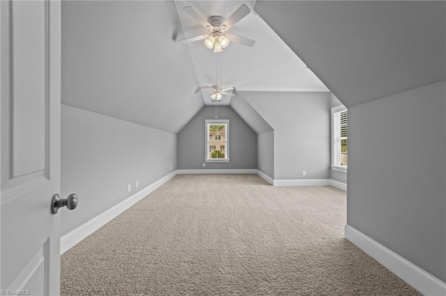 bonus room with vaulted ceiling, carpet flooring, a ceiling fan, and baseboards