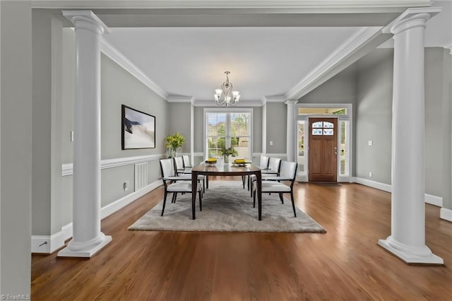 dining space with crown molding, ornate columns, and wood finished floors