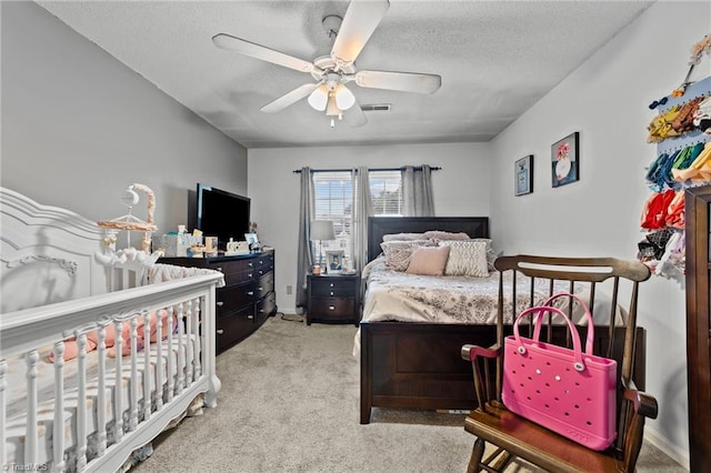 carpeted bedroom featuring ceiling fan and a textured ceiling