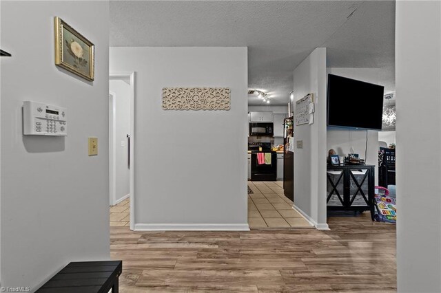 corridor with light hardwood / wood-style flooring and a textured ceiling