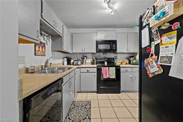 kitchen with a textured ceiling, light tile patterned floors, sink, and black appliances