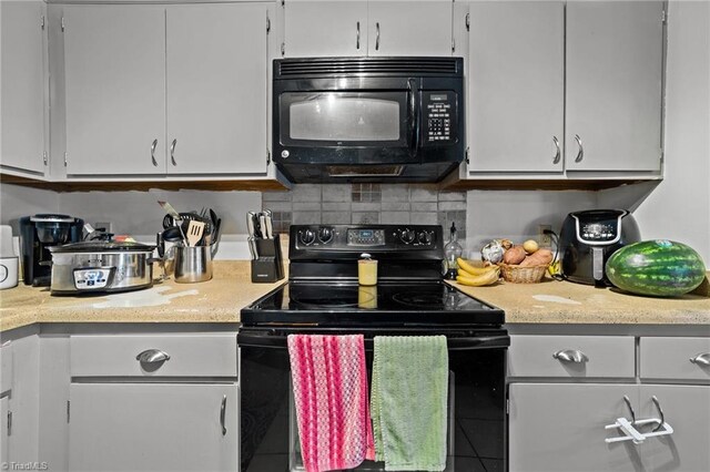 kitchen with black appliances, light stone countertops, and decorative backsplash