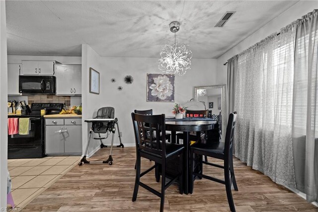 dining space with light wood-type flooring and an inviting chandelier