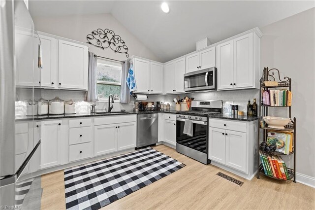 kitchen featuring white cabinets, sink, light hardwood / wood-style flooring, stainless steel appliances, and decorative backsplash