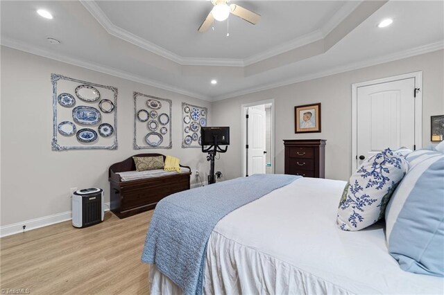 bedroom with ceiling fan, a tray ceiling, crown molding, and light hardwood / wood-style floors