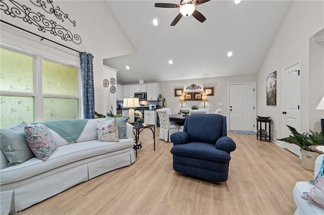 living room with ceiling fan, light hardwood / wood-style floors, and high vaulted ceiling