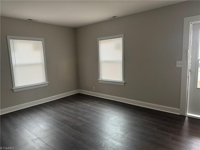 spare room with dark hardwood / wood-style floors and a healthy amount of sunlight