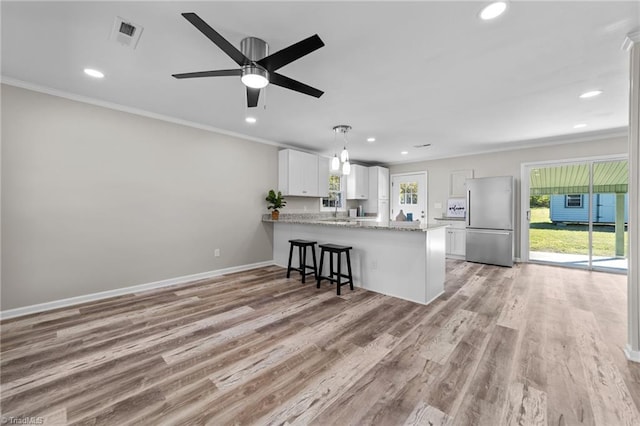 kitchen featuring kitchen peninsula, crown molding, white cabinets, light hardwood / wood-style floors, and stainless steel refrigerator