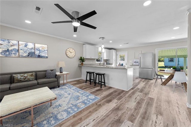 living room with ornamental molding, light hardwood / wood-style flooring, and ceiling fan