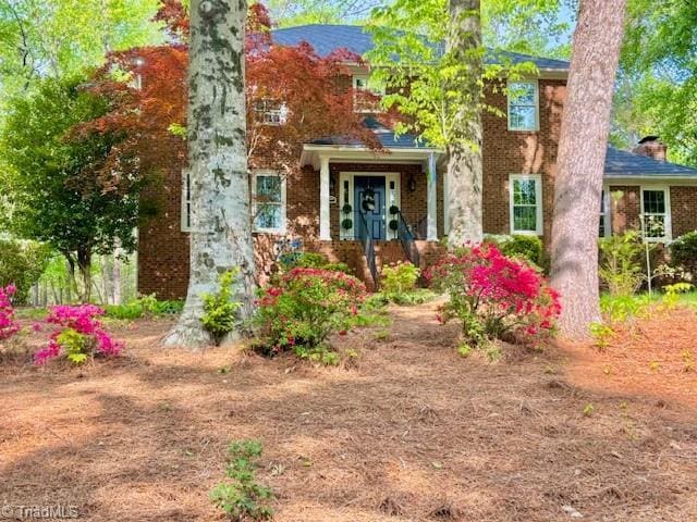 view of exterior entry with brick siding and a chimney