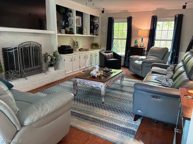 living area with a brick fireplace and wood finished floors