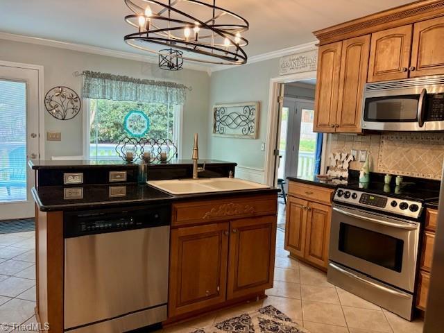 kitchen featuring brown cabinets, light tile patterned flooring, a notable chandelier, appliances with stainless steel finishes, and a sink