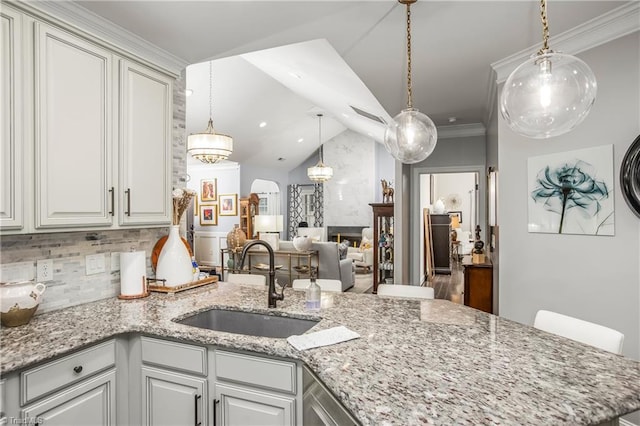 kitchen with arched walkways, lofted ceiling, backsplash, a large fireplace, and a sink