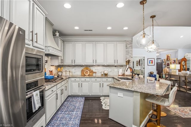 kitchen featuring decorative backsplash, appliances with stainless steel finishes, dark wood-type flooring, a kitchen bar, and a sink