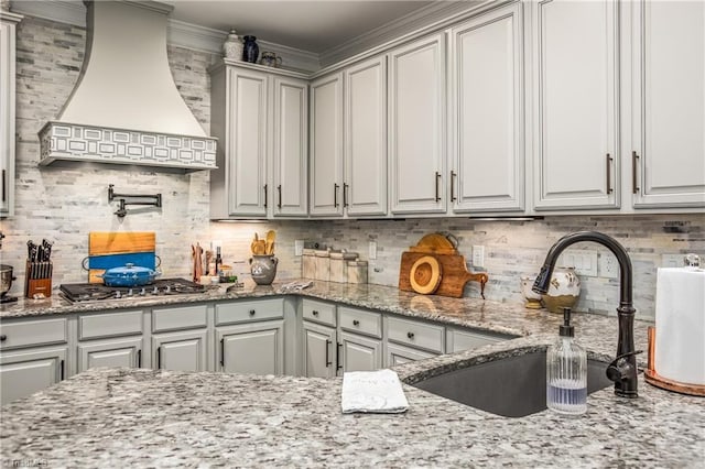 kitchen featuring gray cabinets, premium range hood, and stainless steel gas stovetop