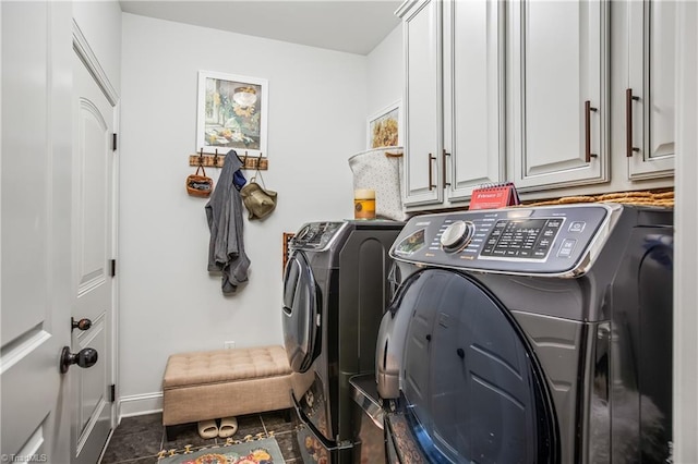 washroom with cabinet space, independent washer and dryer, dark tile patterned floors, and baseboards