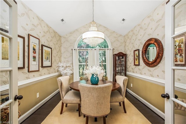 dining area with lofted ceiling, visible vents, wood finished floors, baseboards, and wallpapered walls