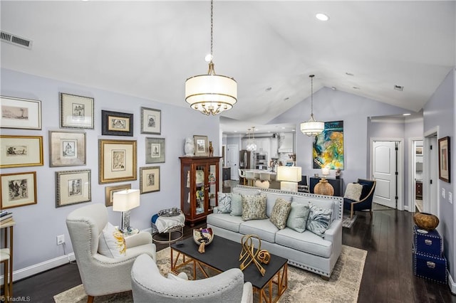 living area with lofted ceiling, wood finished floors, visible vents, baseboards, and an inviting chandelier