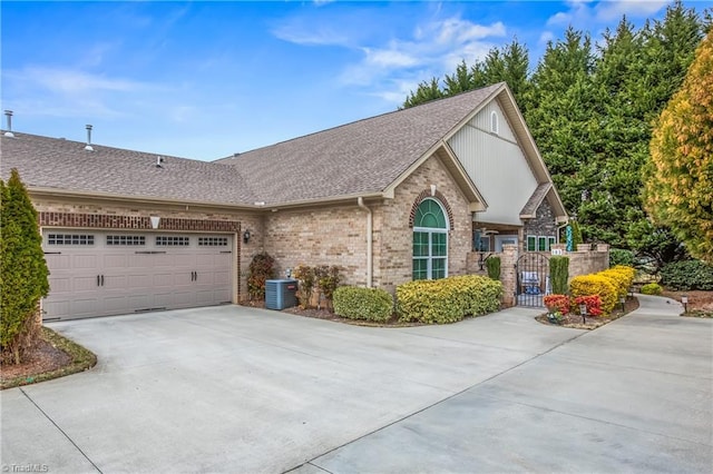 view of front of property with a garage, concrete driveway, roof with shingles, a gate, and brick siding