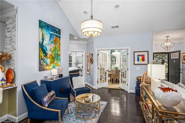 sitting room with baseboards, visible vents, lofted ceiling, wood finished floors, and a chandelier