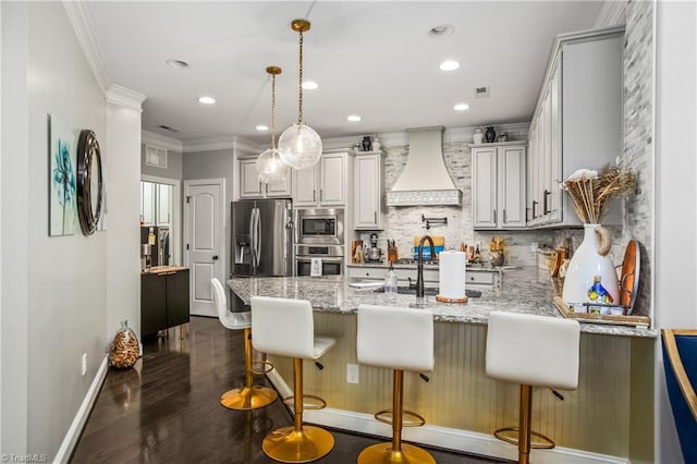 kitchen featuring light stone counters, stainless steel appliances, premium range hood, a peninsula, and backsplash