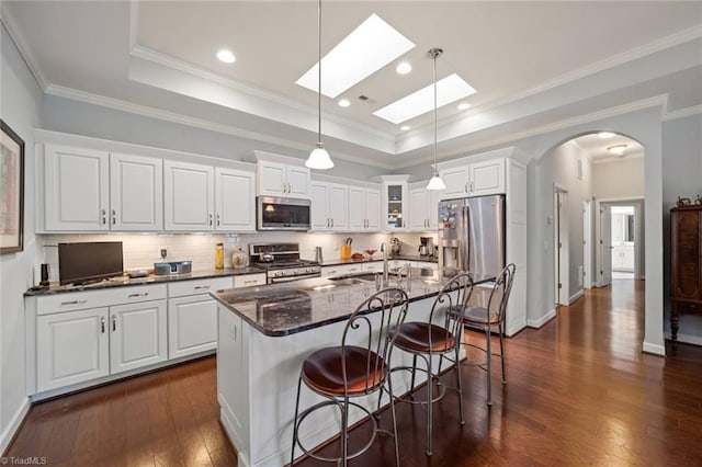 5905 Knowledge Dr, Clemmons, NC 27012 - kitchen with appliances with stainless steel finishes, dark wood finished floors, a skylight, arched walkways, and backsplash