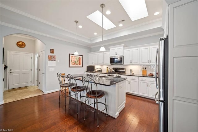 5905 Knowledge Dr, Clemmons, NC 27012 - kitchen featuring stainless steel appliances, arched walkways, dark countertops, a sink, and a breakfast bar area