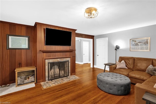 living room with a tile fireplace, wood finished floors, and baseboards