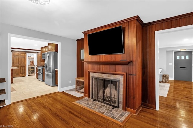 unfurnished living room with baseboards, a tile fireplace, and light wood finished floors