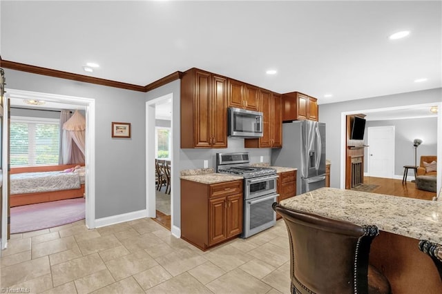 kitchen with stainless steel appliances, plenty of natural light, baseboards, light stone countertops, and recessed lighting