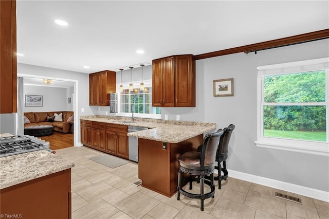 kitchen featuring dishwasher, a kitchen bar, a peninsula, light stone counters, and brown cabinetry