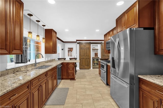 kitchen with appliances with stainless steel finishes, a sink, light stone counters, a peninsula, and decorative light fixtures