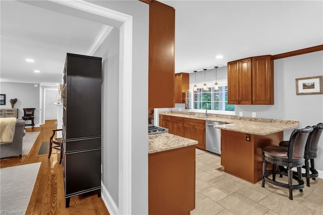 kitchen with appliances with stainless steel finishes, ornamental molding, brown cabinetry, a kitchen breakfast bar, and a peninsula