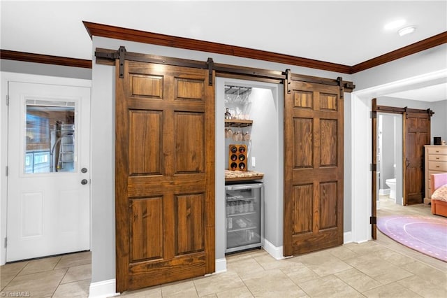 indoor dry bar featuring a barn door, wine cooler, crown molding, light tile patterned floors, and baseboards