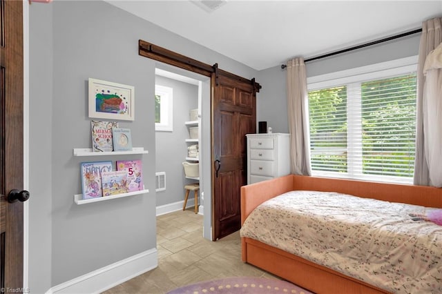 bedroom featuring a barn door and baseboards