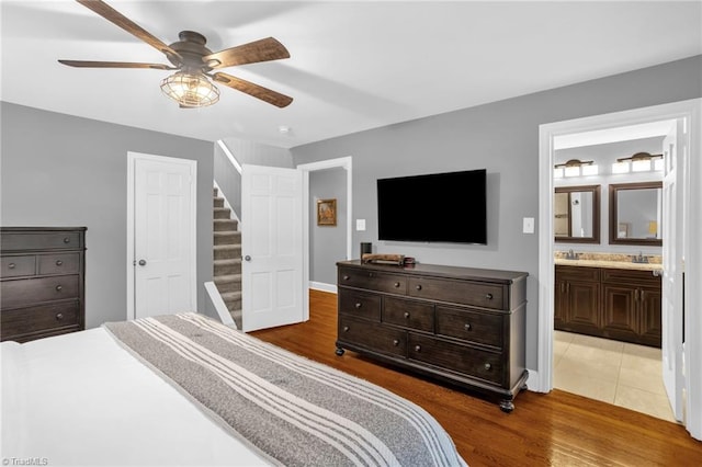 bedroom with light wood-style flooring, ensuite bathroom, a sink, and ceiling fan