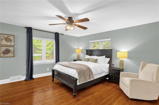 bedroom with multiple windows, baseboards, wood finished floors, and a ceiling fan
