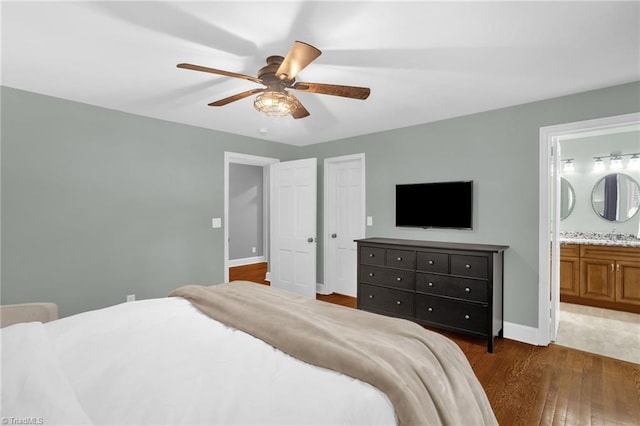 bedroom featuring dark wood finished floors, baseboards, connected bathroom, ceiling fan, and a closet