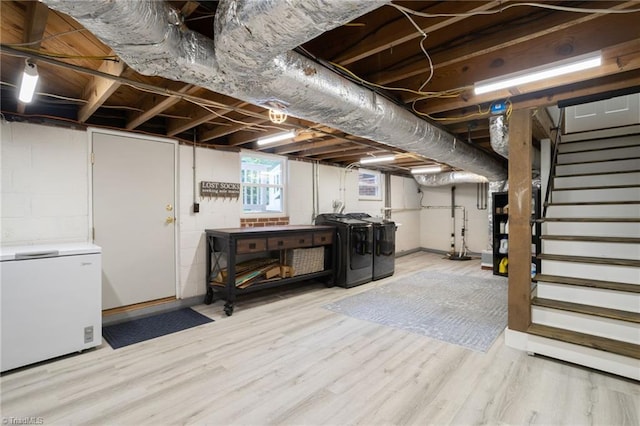 below grade area featuring fridge, independent washer and dryer, wood finished floors, and stairway