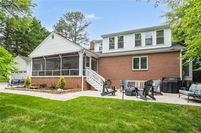 back of property featuring a sunroom, a patio, brick siding, and a lawn