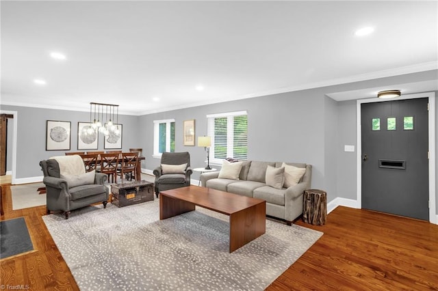 living area featuring crown molding, wood finished floors, baseboards, recessed lighting, and a chandelier