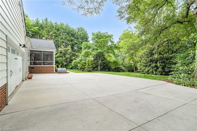 view of patio / terrace featuring a sunroom and view of scattered trees