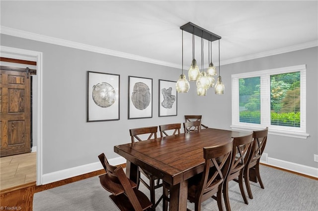 dining room featuring crown molding, a barn door, baseboards, and light wood-type flooring