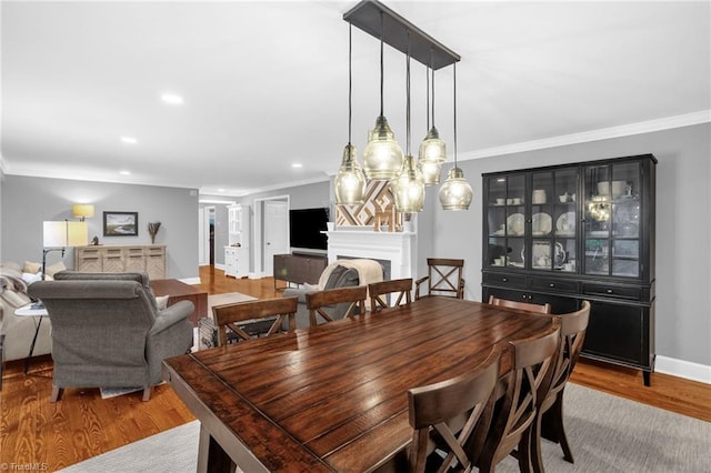 dining space with a fireplace, crown molding, wood finished floors, recessed lighting, and baseboards