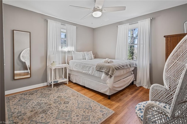 bedroom featuring hardwood / wood-style floors, ceiling fan, and multiple windows